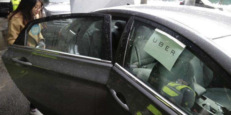 FILE - In this March 15, 2017, file photo,  a passenger enters an Uber car at LaGuardia Airport in New York. Taxi regulators on Tuesday, Dec. 4, 2018, in New York City, approved new minimum pay standards for app-based car services that they say will raise drivers' annual earnings by $10,000 a year. (AP Photo/Seth Wenig, File)