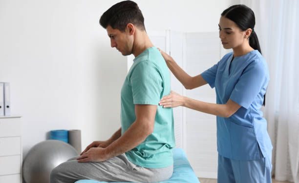 Orthopedist examining man's back in clinic. Scoliosis treatment